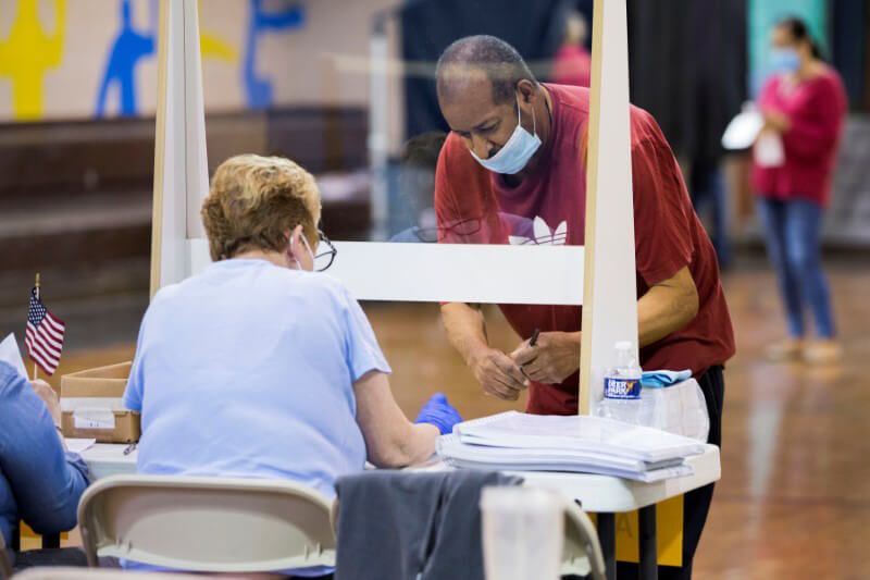 Nh&acirc;n vi&ecirc;n bầu cử (ngồi) hướng dẫn cử tri đi bầu ở Philadelphia năm 2020. Ảnh: Reuters.