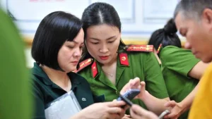Cán bộ công an Hà Nội hướng dẫn người dân cài đặt ứng dụng VNeID. Ảnh: Hoang Phong / Báo Nhân Dân.